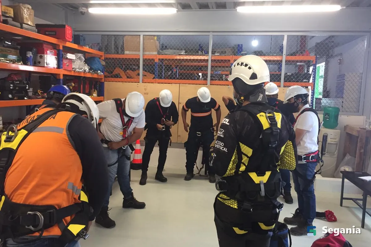 Grupo de trabajadores con arnés y casco revisando su equipo